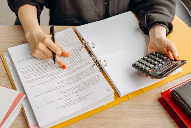 A pair of hands writing on a piece of paper and holding a calculator